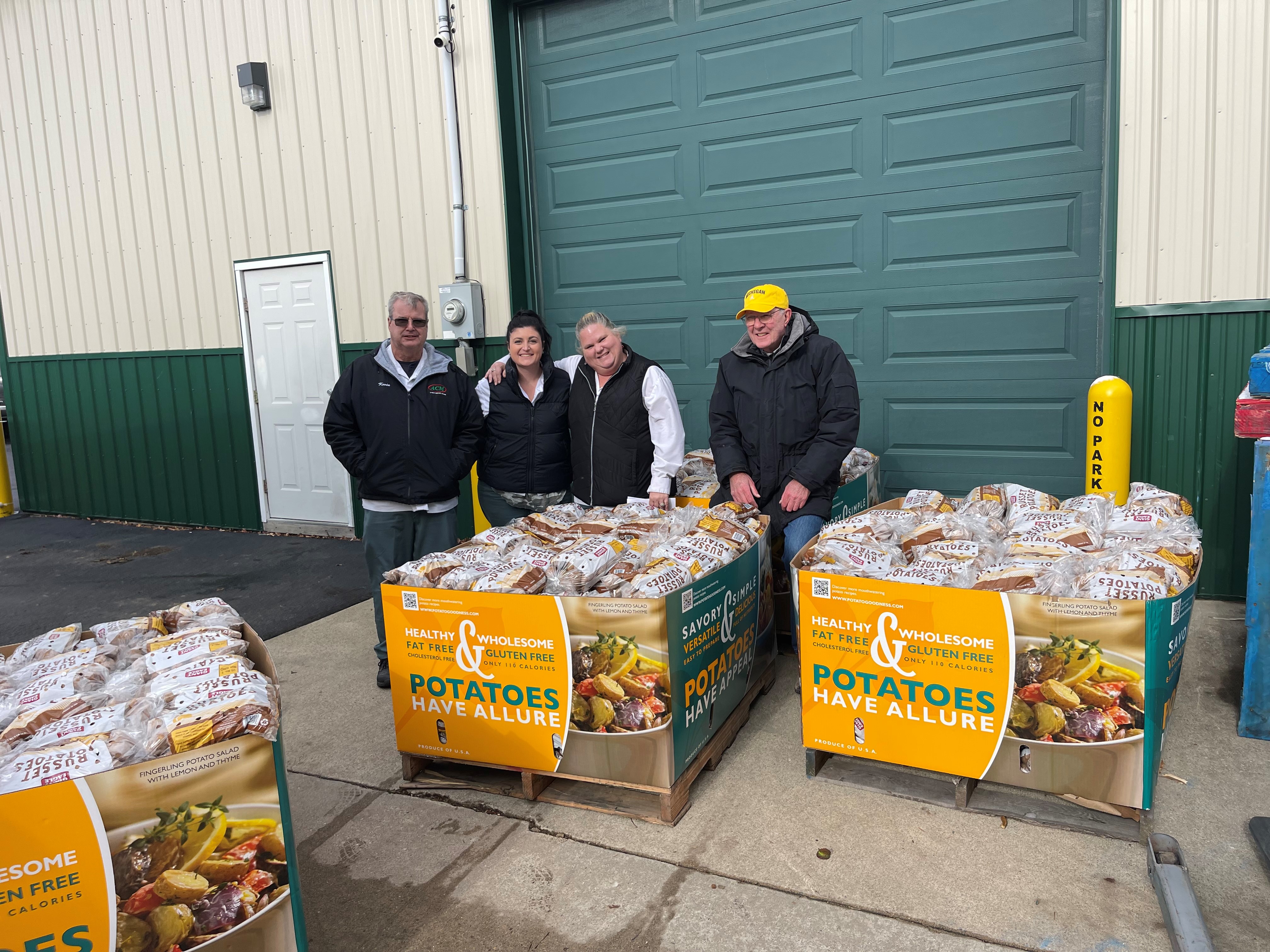 ACM workers standing behind a box of packaged potatoes