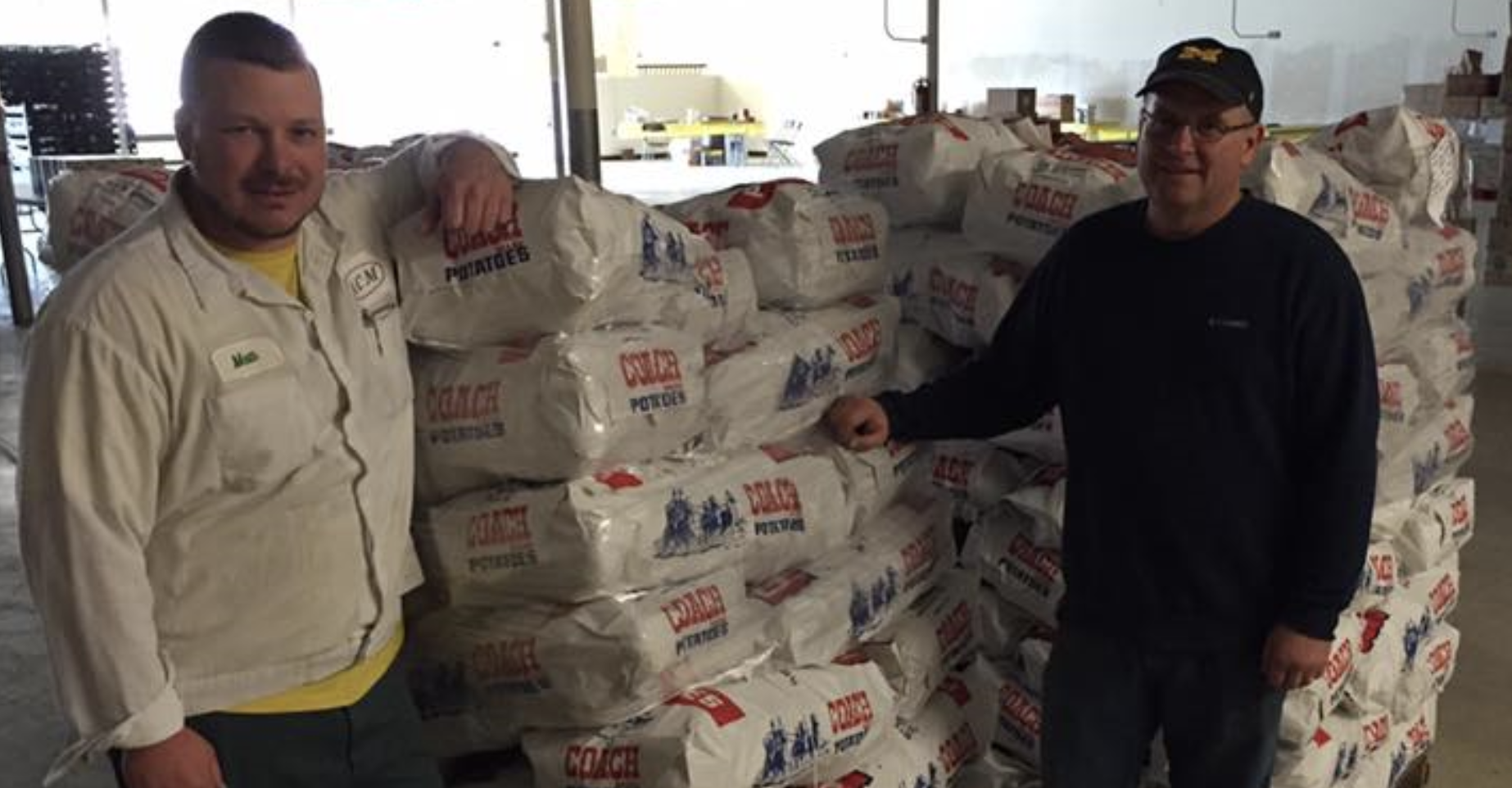 ACM workers standing in front of a stack of packaged potatoes