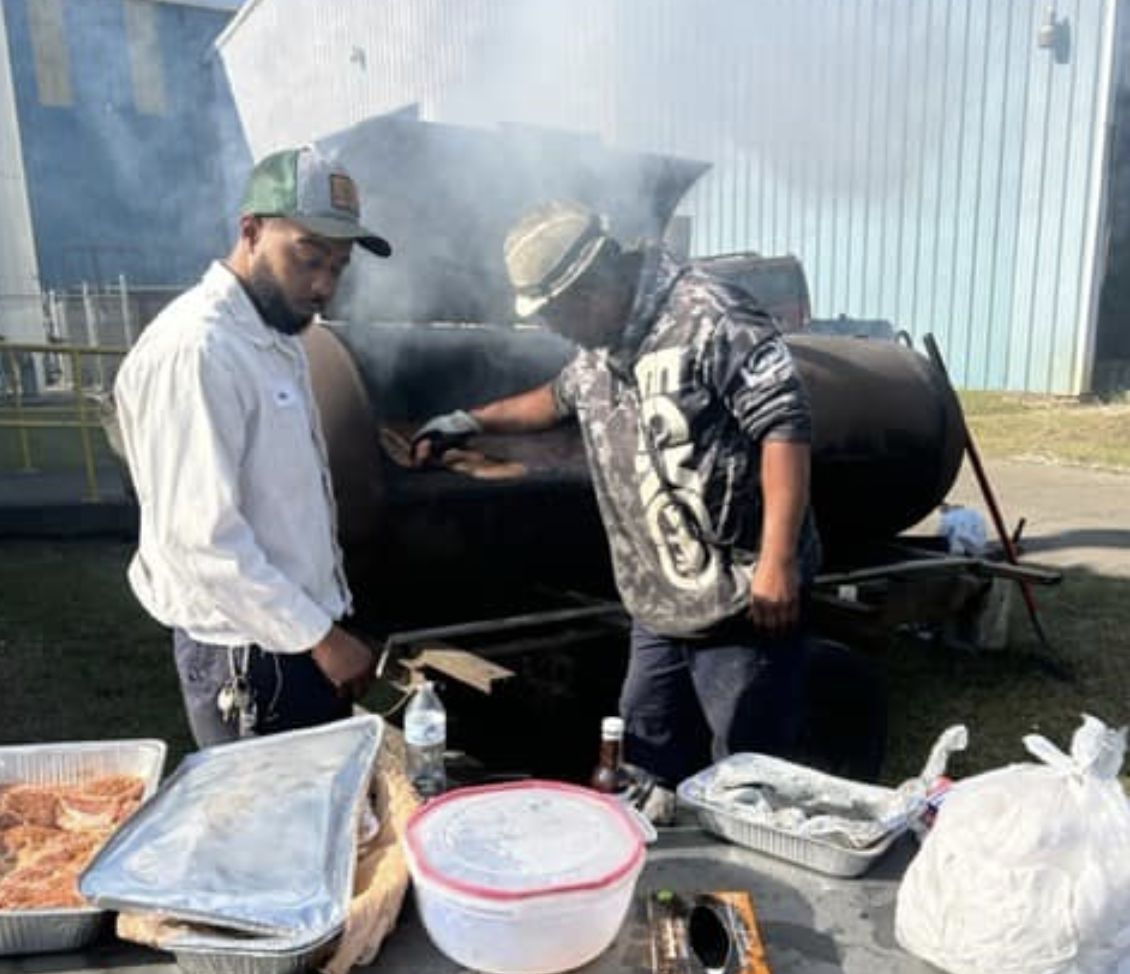 Two men cooking food on a grill